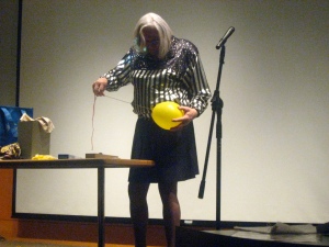 Mary Magician sticks a needle through a balloon without breaking it.
